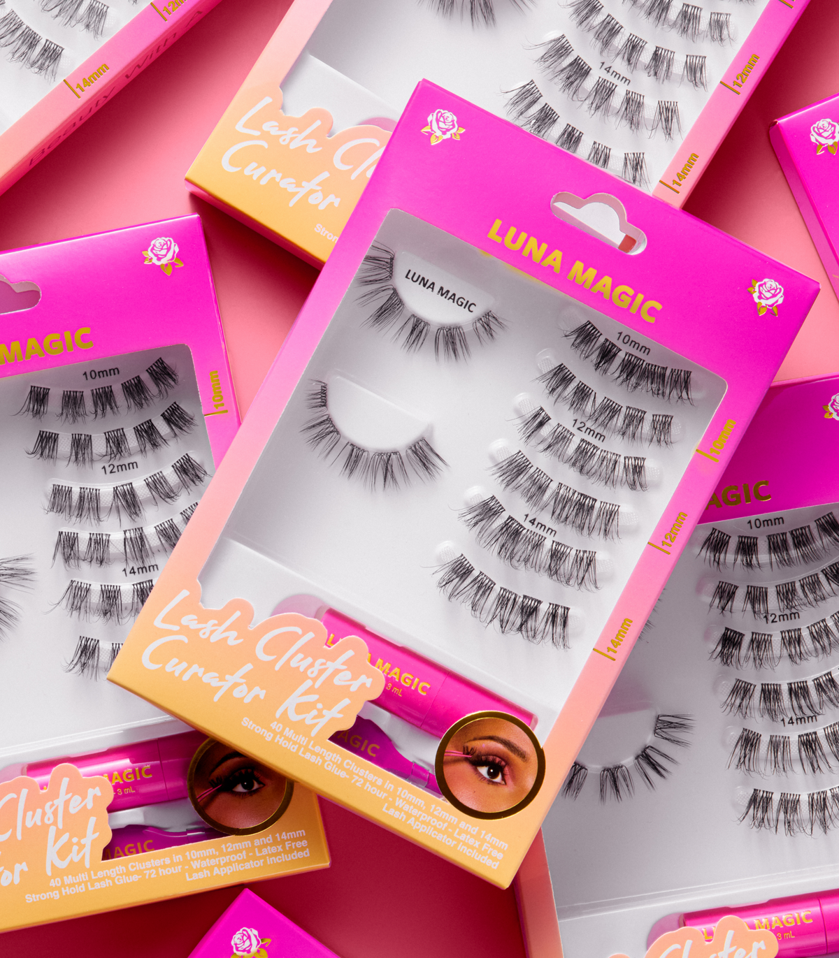 A set of false eyelash clusters in retail packaging, arranged in a styled flat-lay. The packaging is bright pink and orange with the brand name 'Luna Magic' clearly visible.
